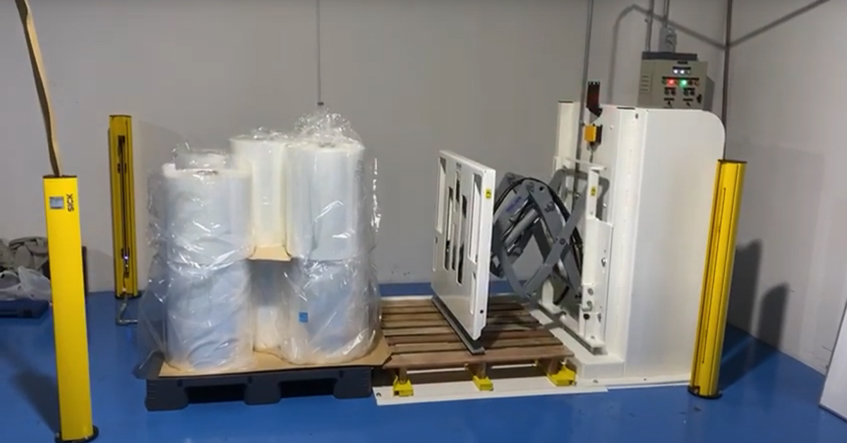 Horizontal slip-sheeted pallet changer used to transfer goods from plastic to wooden pallets in cleanrooms.